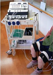 ベルト電極を脚に巻いてオートテンズ プロで治療を受ける様子